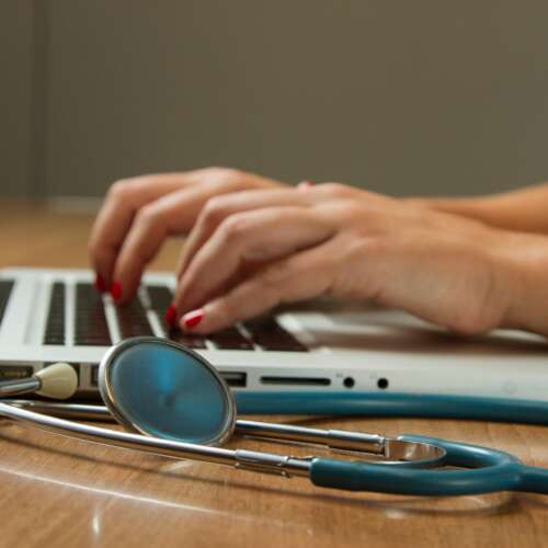Rechtenvrije afbeelding van een dokter achter een laptop door National Cancer Institute via Unsplash.