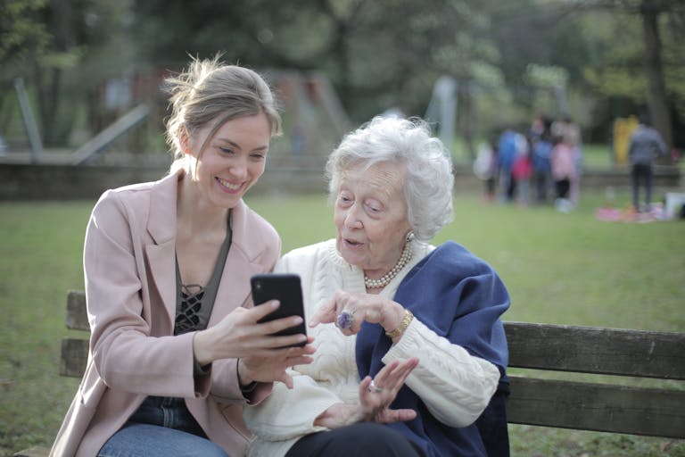 Rechtenvrije foto van jonge vrouw helpt oudere dame met haar mobiele telefoon.